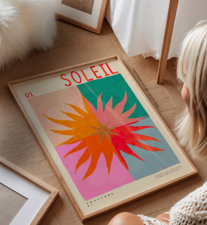 Framed colorful poster with 'Soleil' text on a wooden floor.