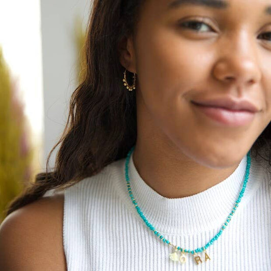 Woman wearing a turquoise beaded necklace with gold charms