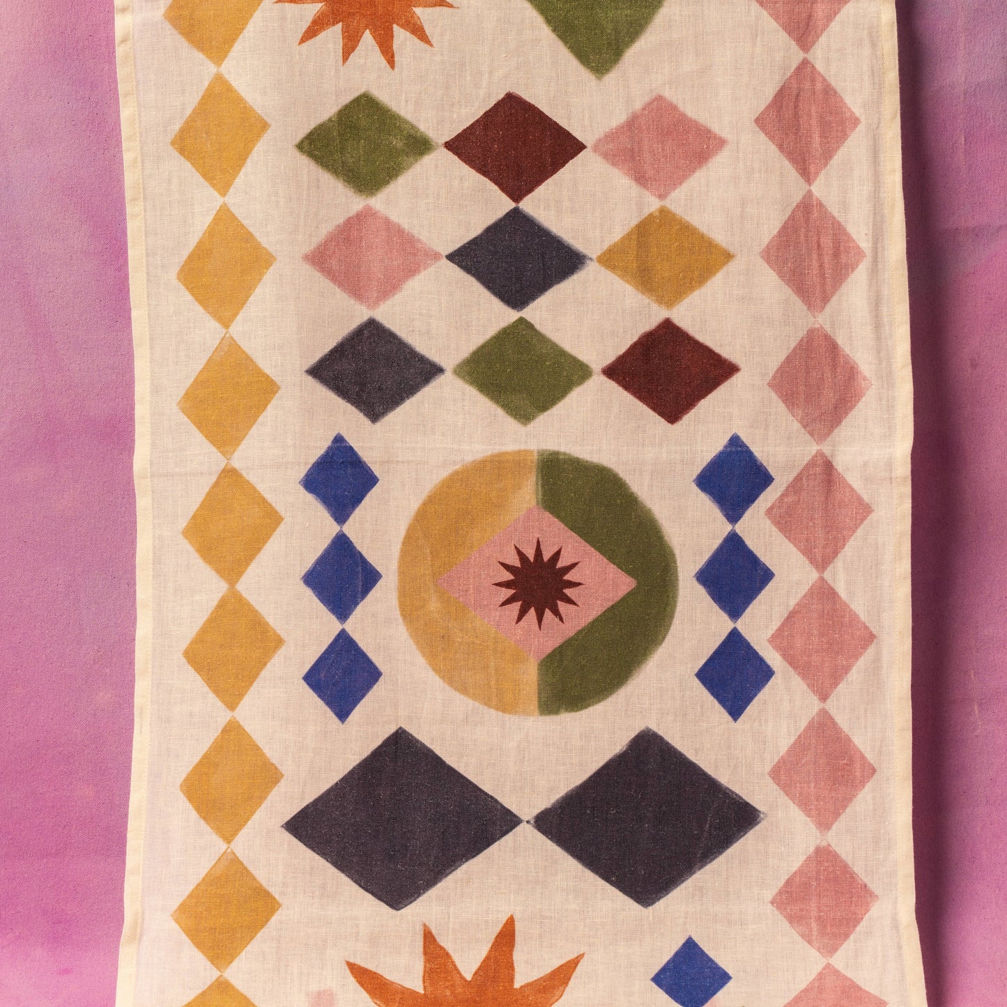 Geometric patterned fabric with colorful shapes on a pink background