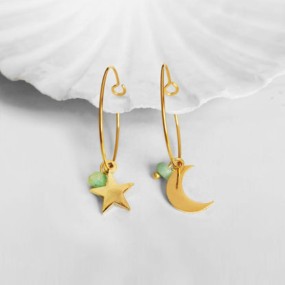 Gold earrings with star and moon charms on a white background