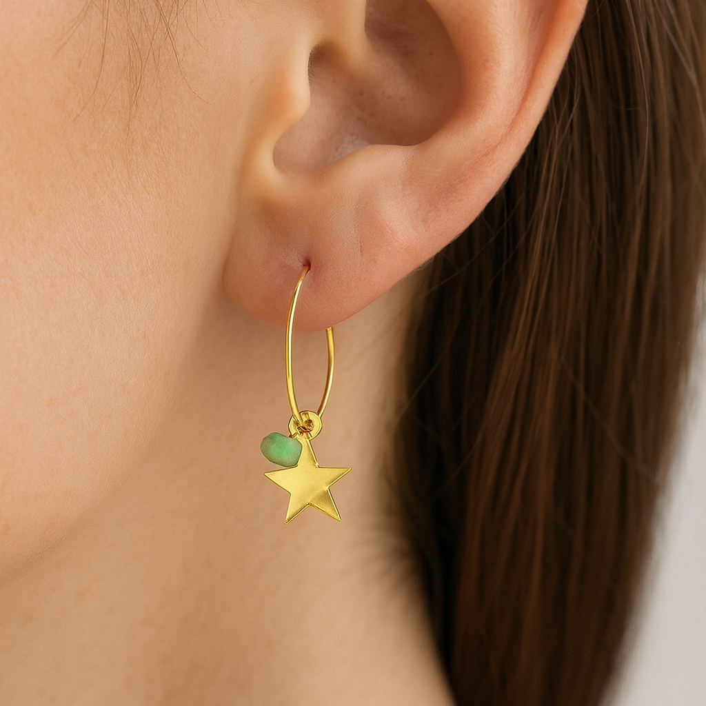 Gold hoop earring with a star and green amazonite charm worn by a person.