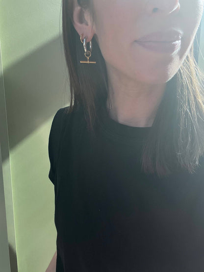 Person wearing gold hoop earrings with a neutral background