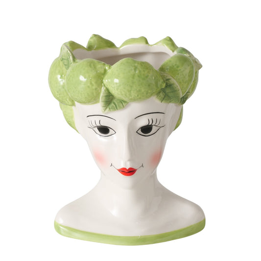Vase shaped like a woman's head with green limes on a white background