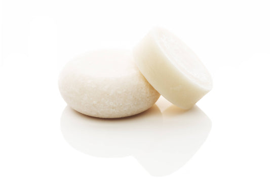 shampoo and conditioner bar on a reflective surface with a blurred background