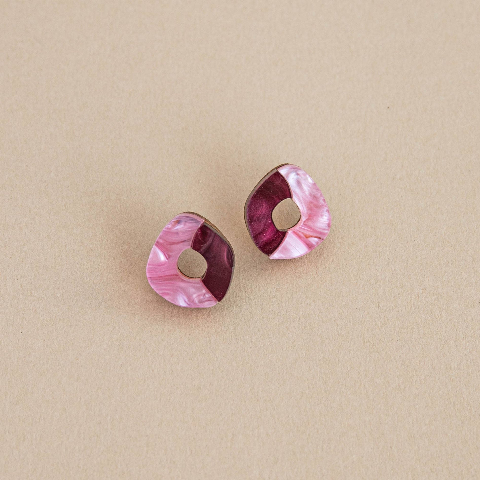 Pair of pink and purple geometric earrings on a beige background