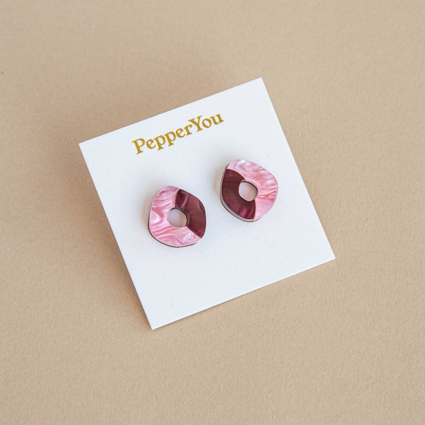 Pink marbled earrings on a 'PepperYou' branded card against a beige background