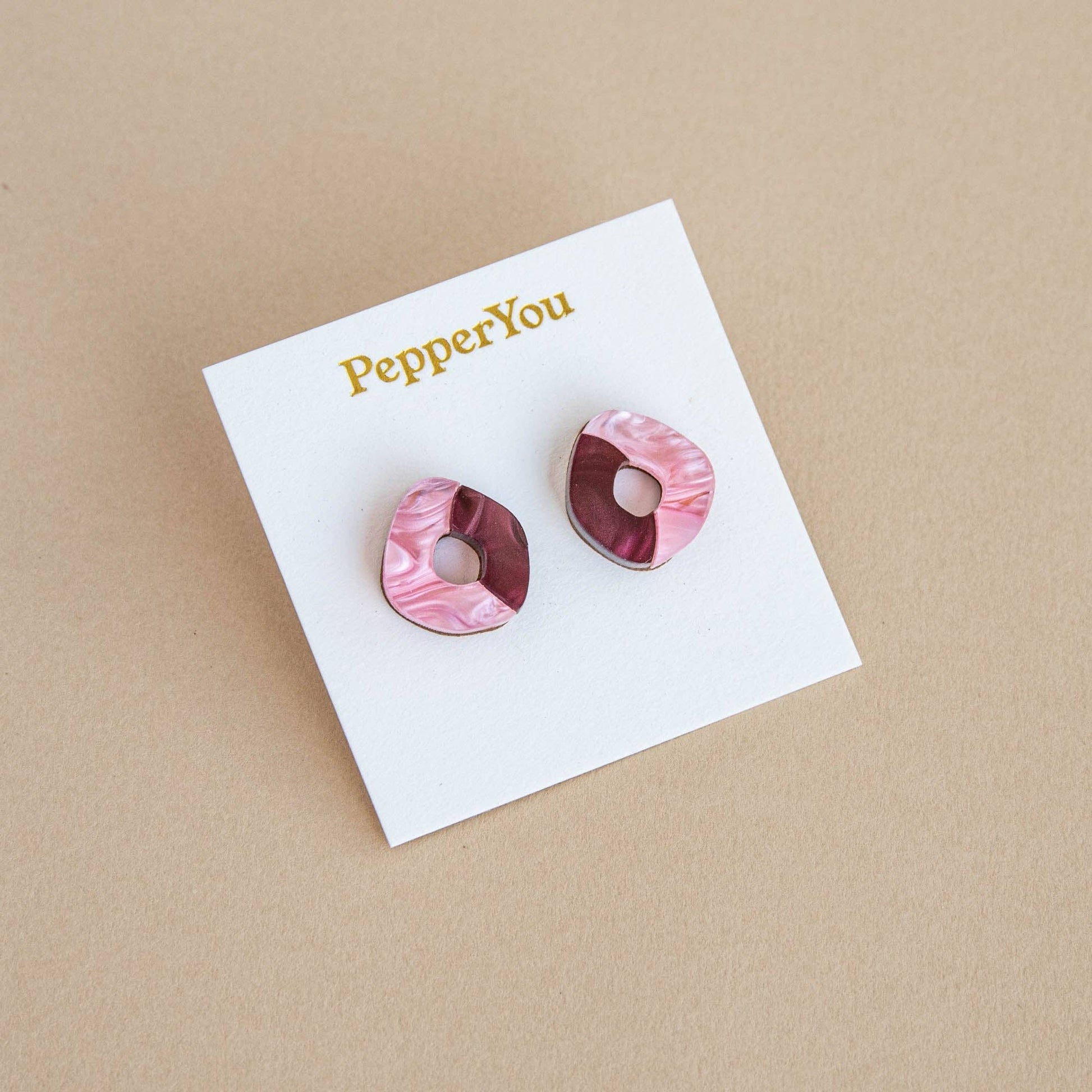 Pink marbled earrings on a 'PepperYou' branded card against a beige background