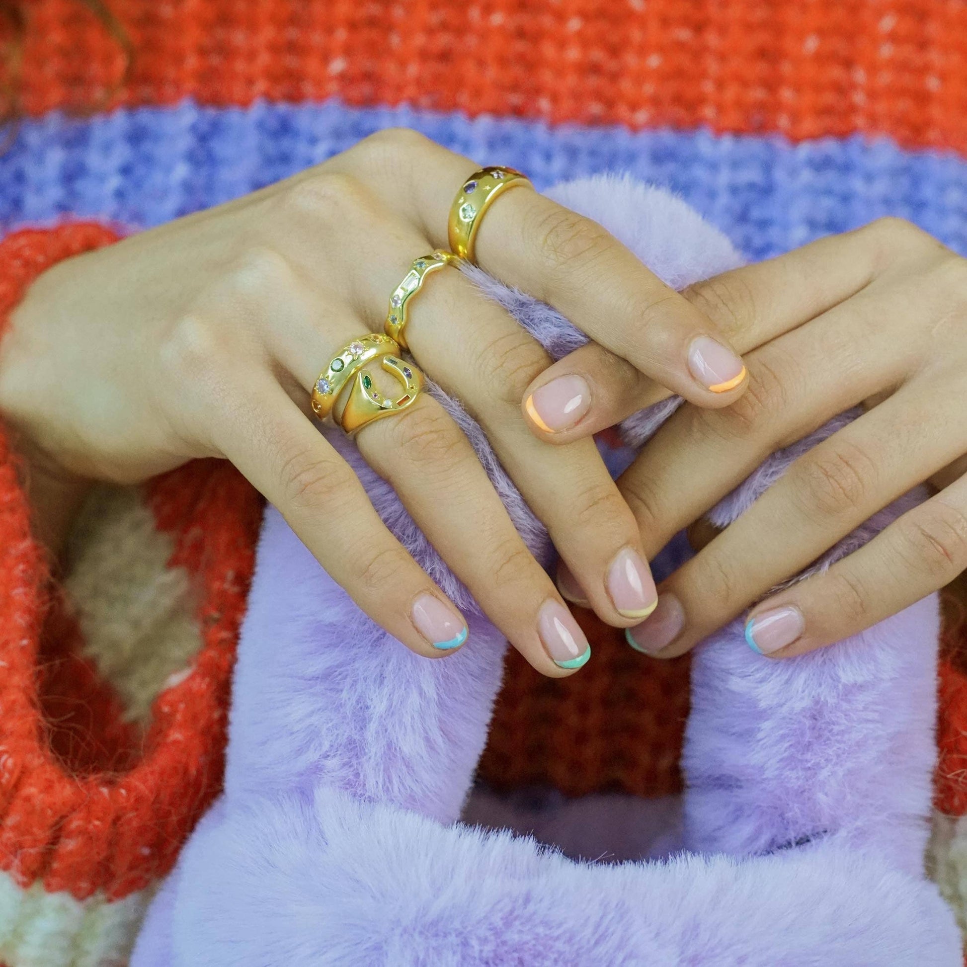 Close-up of a hand with gold rings on a colorful fabric background