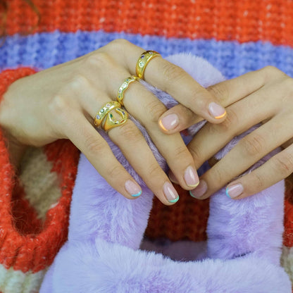 Close-up of a hand with gold rings on a colorful fabric background