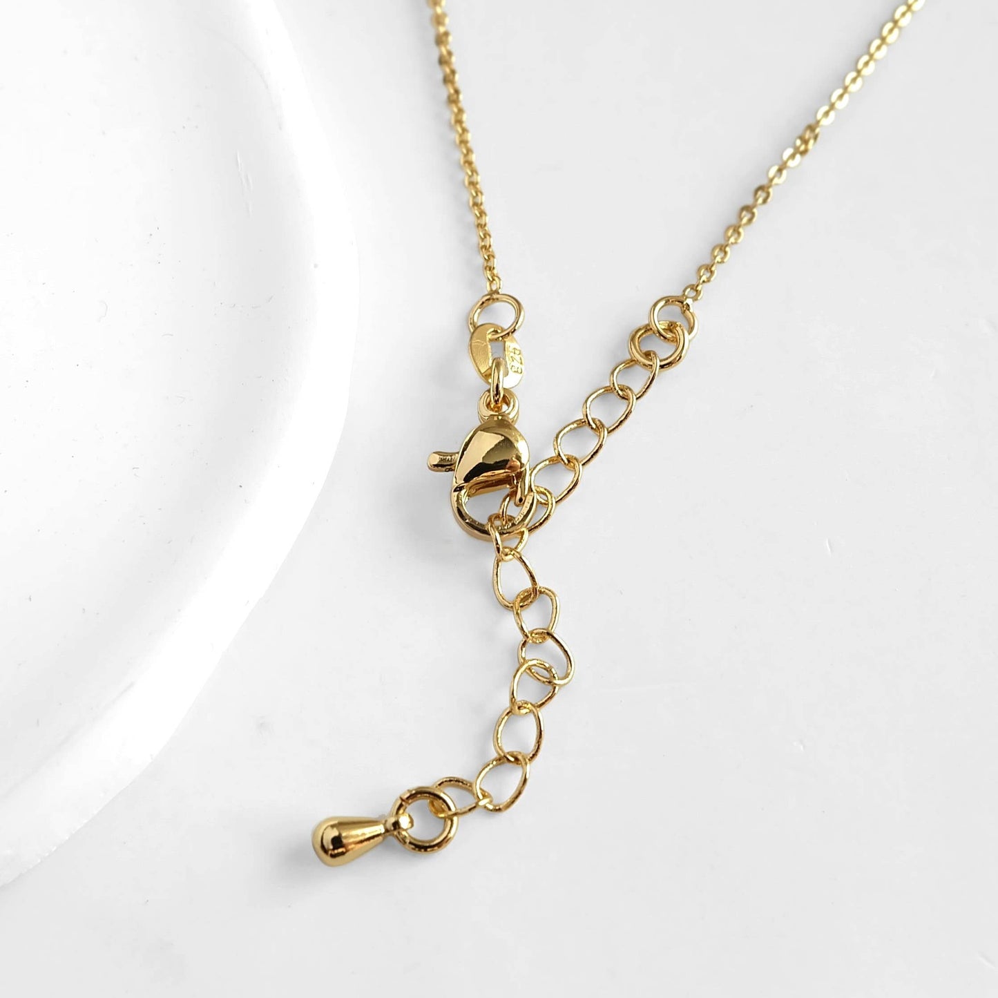 Gold necklace with a heart-shaped clasp on a white background