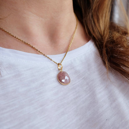 Necklace with a pink pendant worn by a person on a white background