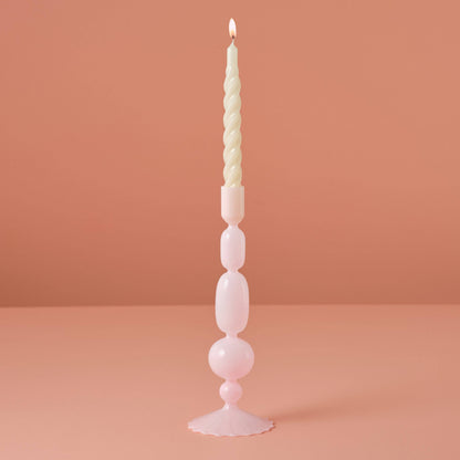Tall, decorative candle with a unique design on a pink background