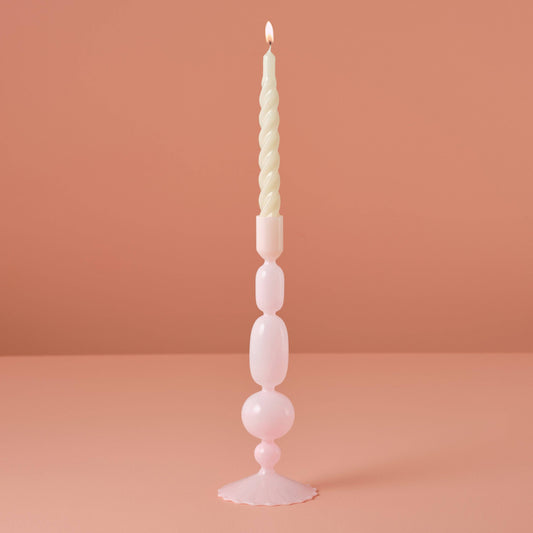 Tall, decorative candle with a unique design on a pink background