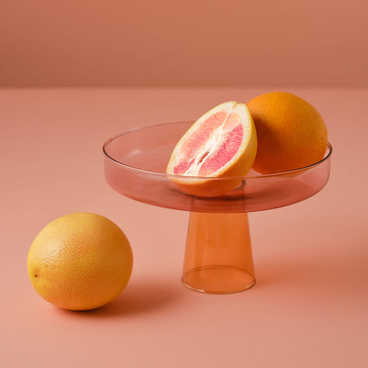 Grapefruit on a glass stand with a pinkish background