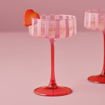 Pink striped cocktail glass with a strawberry on a pink background