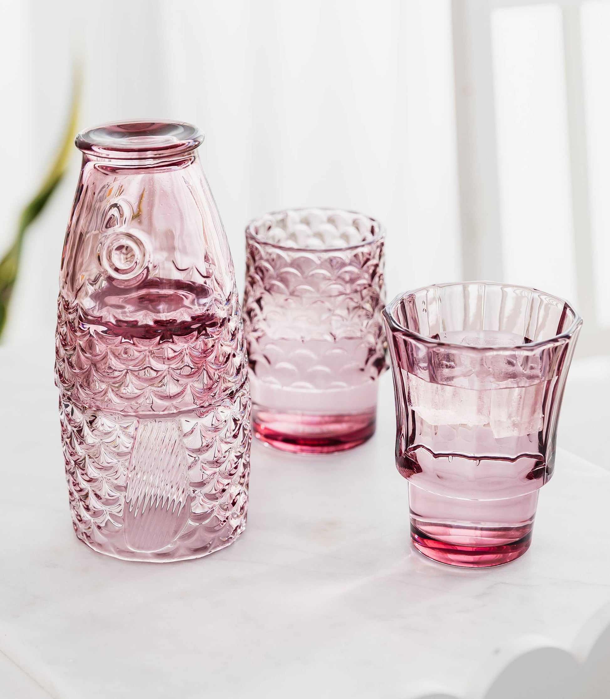 Set of Pink_fish_stackable_glasses with water in on a table.