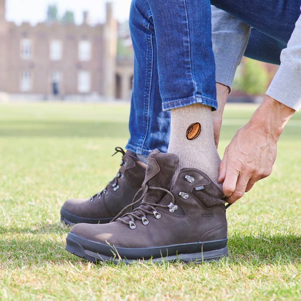 Person putting on brown hiking boots in a grassy area