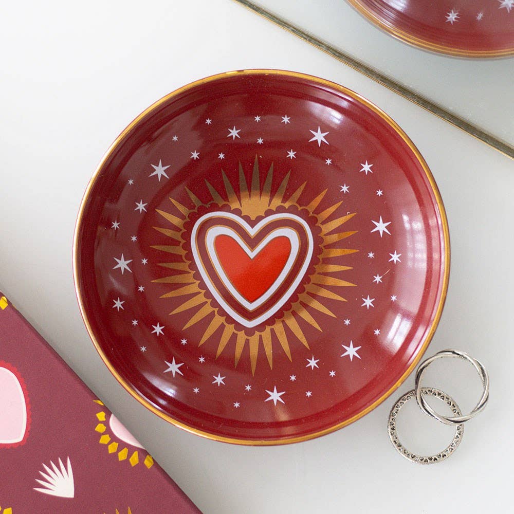 Red decorative plate with a heart and star design on a white surface.