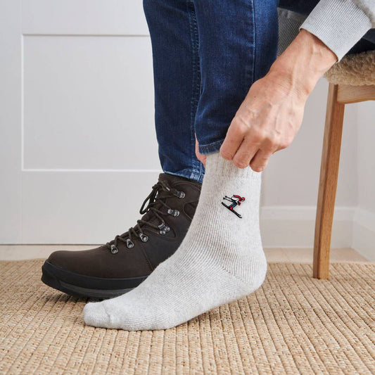 Person wearing a gray sock with a golf design, sitting on a chair indoors.