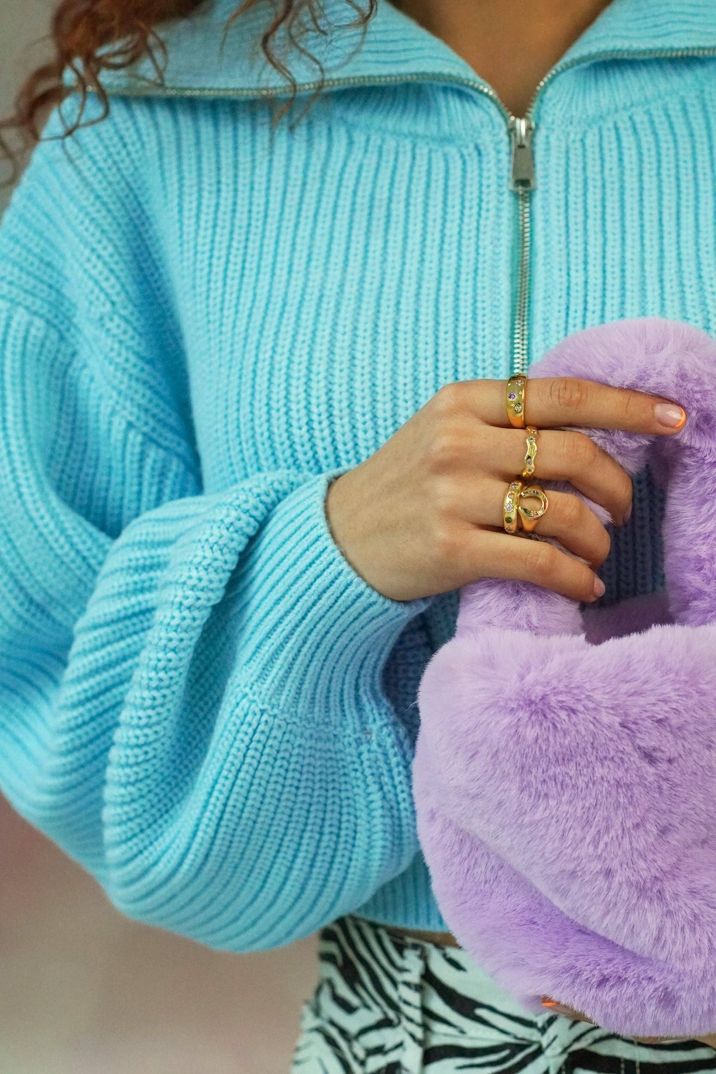 Person wearing a light blue sweater holding a purple fluffy object.