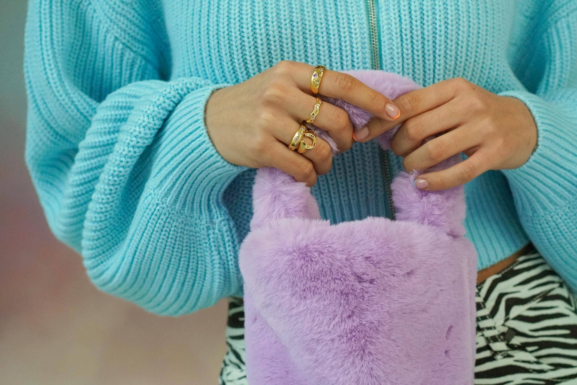 Person wearing a light blue sweater holding a pink fluffy object.