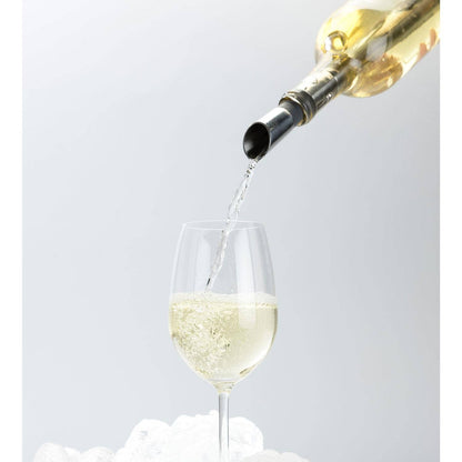 White wine being poured from a bottle into a glass against a light gray background