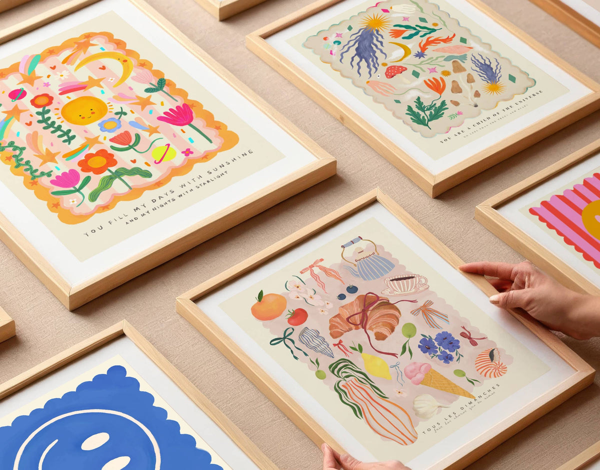 Framed illustrations on a wooden surface with a hand reaching for one of them.