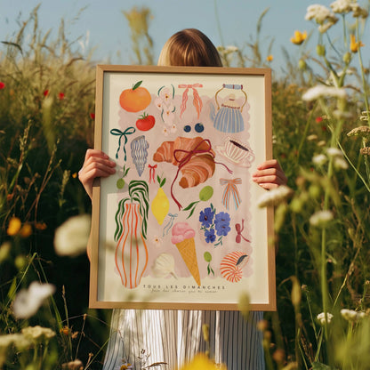 Person holding a framed illustration in a field of flowers