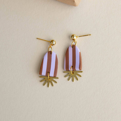 Pair of earrings with striped design and gold accents on a beige background