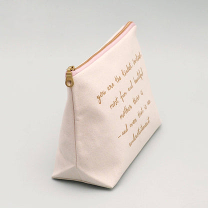 Cream make up pouch with gold text on a light gray background