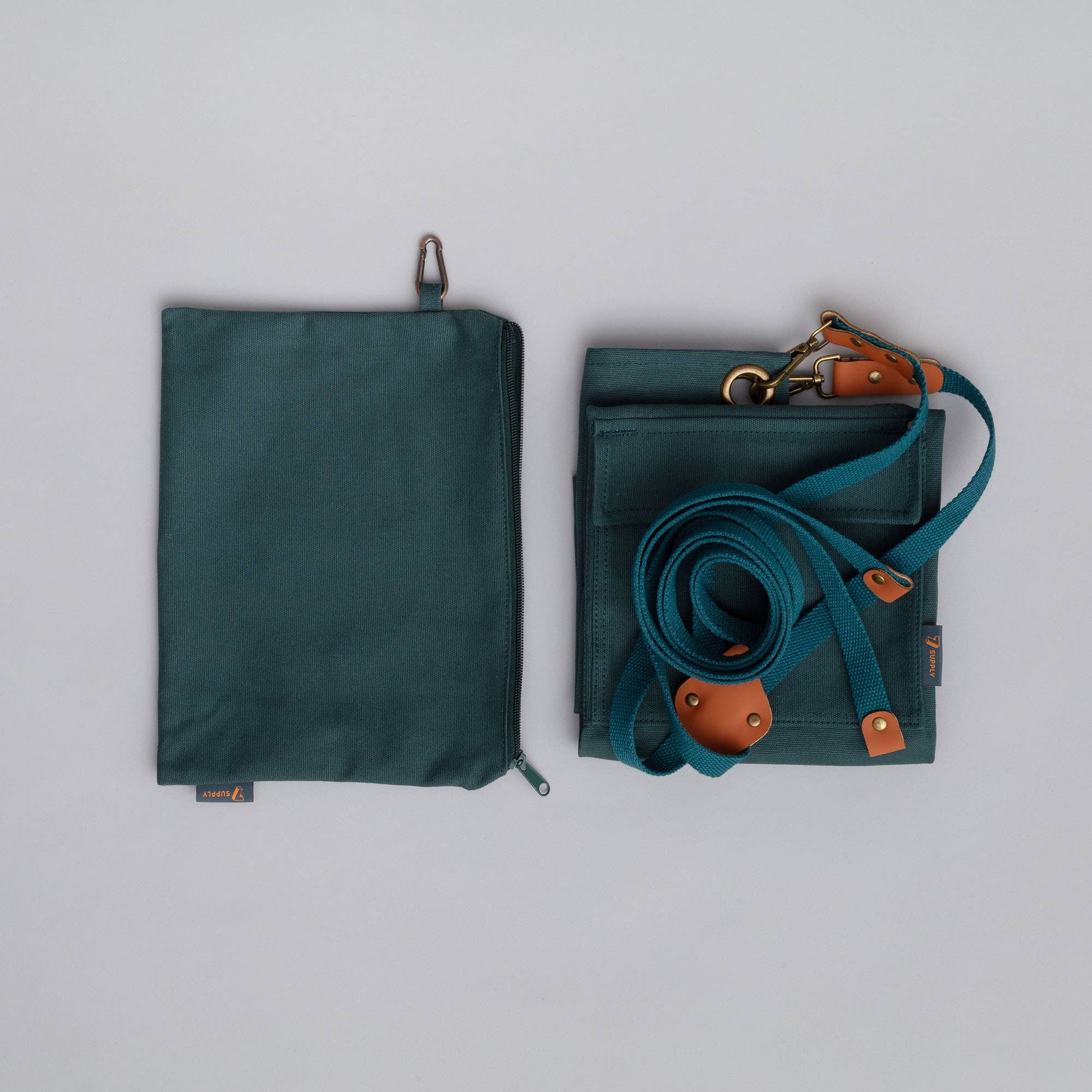 Green bag with strap and brown leather accents on a gray background