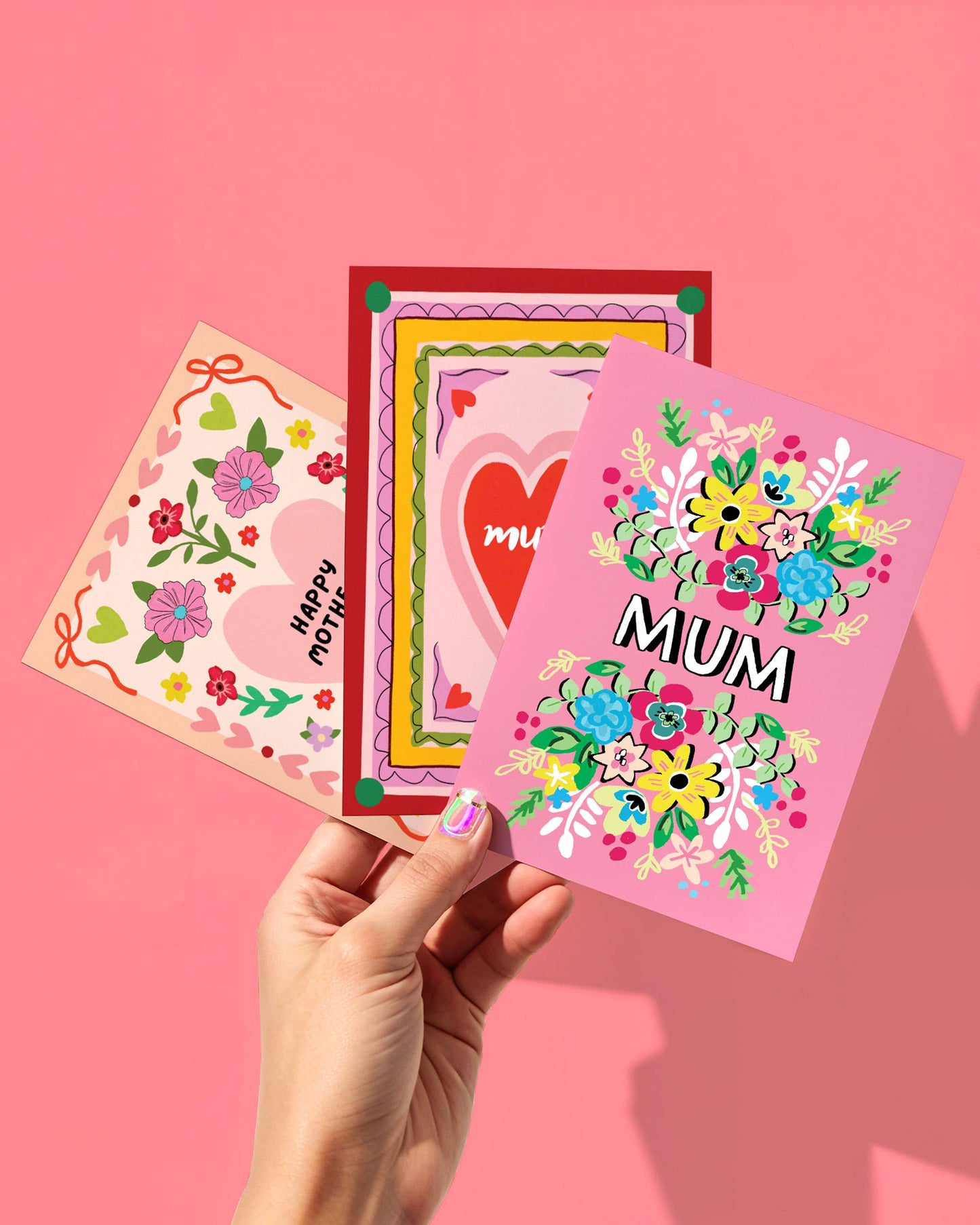 Three colorful greeting cards with floral designs and text on a pink background.